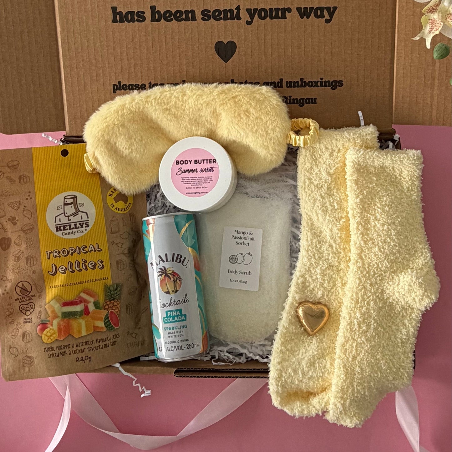 Tropical gift box includes cocktail, sleep mask, tropical lollies, mango scrub and socks , body butter