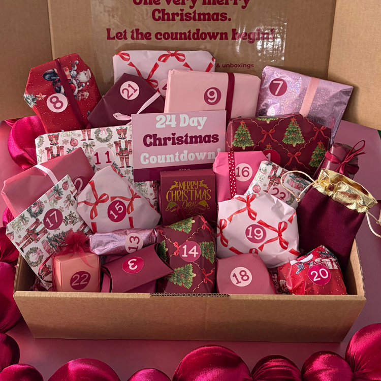 Love Gifting 24-Day Christmas Advent Gift Box filled with individually wrapped and numbered Christmas surprises in pink, burgundy and festive packaging.