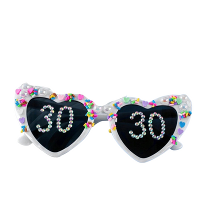 Sunglasses with heart-shaped lenses displaying '30' and colorful embellishments on a white background