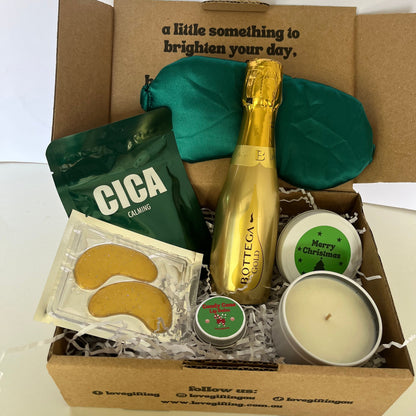 Gift box with a bottle of champagne, candles, and other items on a white background
