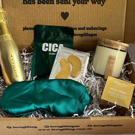 Gift box with various items including a green eye mask, CICA pack, and a candle, with a message on the box.