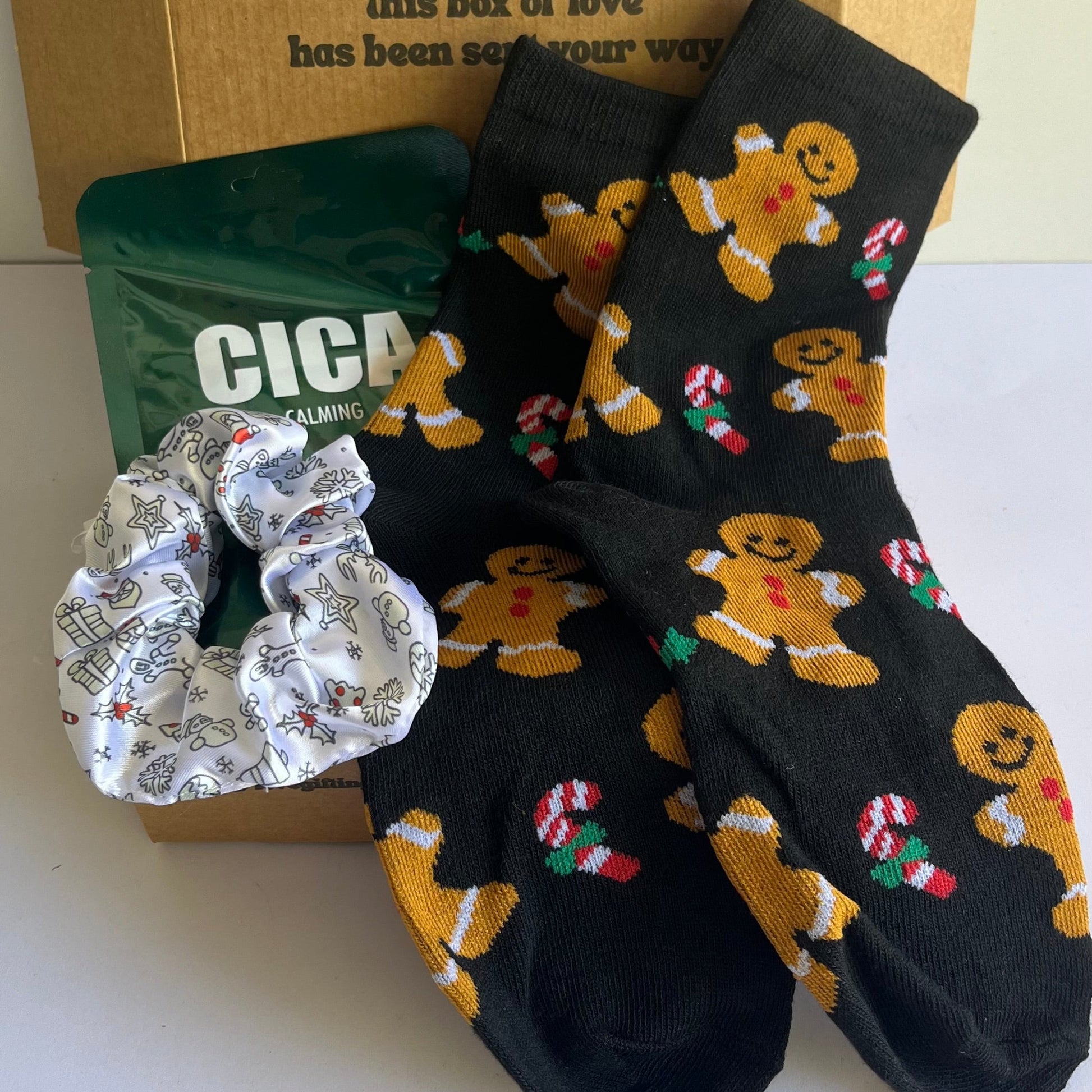 Box with socks, a scrunchie, and a card on a white surface