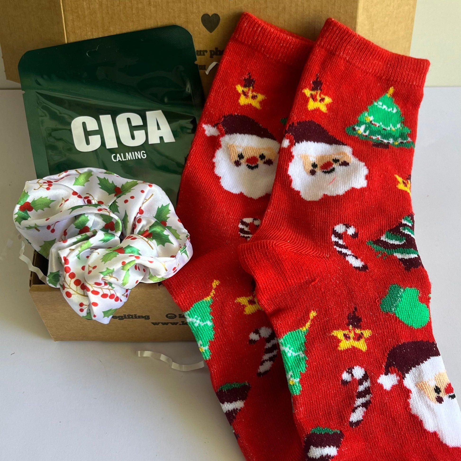 Red Santa Claus socks with green scrunchie and CICA product on a white surface.