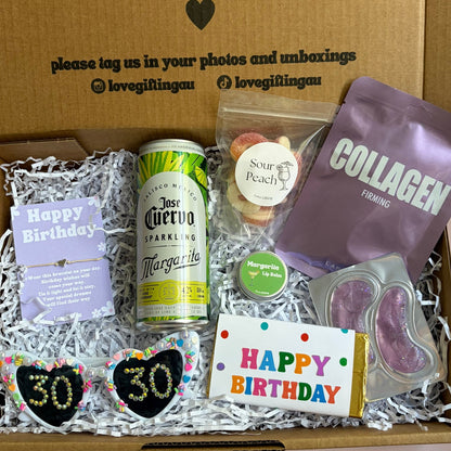 Gift box with birthday-themed items including a can, cookies, and a card, with a message on the lid.