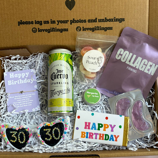 Gift box with birthday-themed items including a can, cookies, and a card, with a message on the lid.