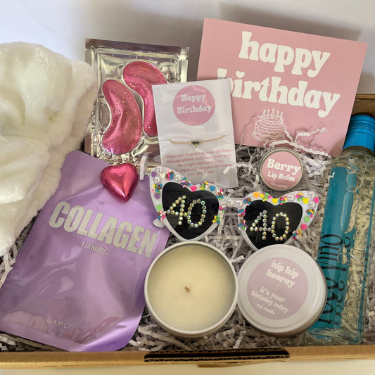 Gift box with various items including a candle, soap, and a bottle of hand sanitizer.
