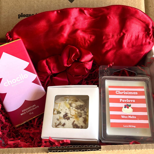 Gift box with red satin bow, chocolates, and photo frames on a textured surface.