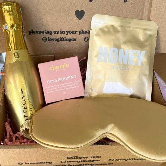 Gift box with champagne, sleep mask, and 'honey' product with a message on the box.