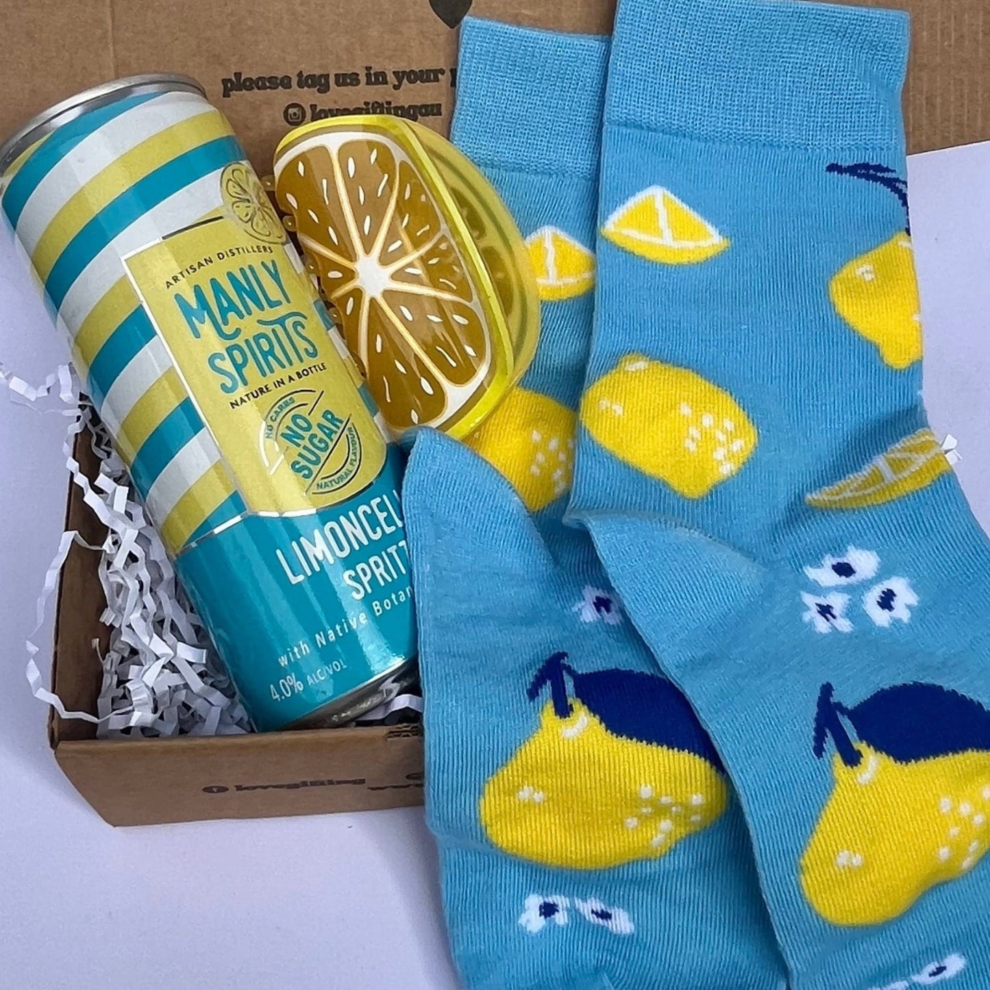 Box with lemon-themed socks and a can of limoncello on a white background