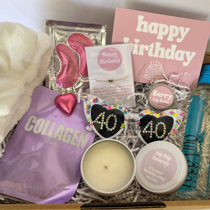Gift box with various items including a candle, soap, and a bottle of hand sanitizer.