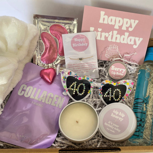 Gift box with various items including a candle, soap, and a bottle of hand sanitizer.