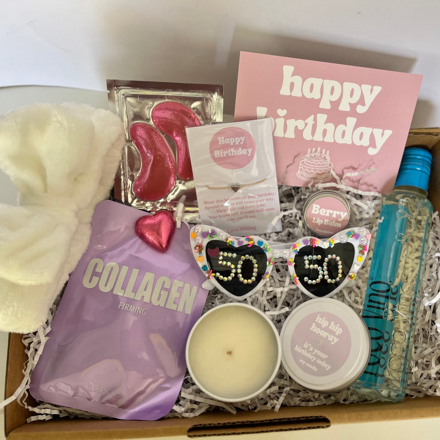 Gift box with various items including a 'happy birthday' card, collagen product, and skincare products.