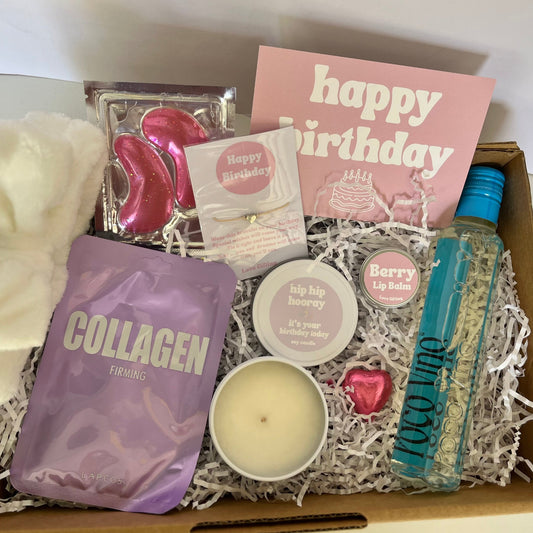Gift box with skincare products, a candle, and 'happy birthday' cards.