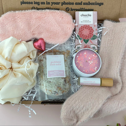 Gifting box with pink eye mask, scrunchie, bath salts, chocolate, energy roller and socks