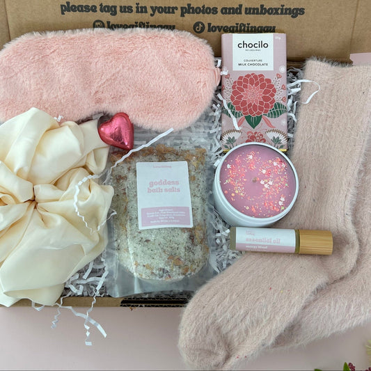 Gifting box with pink eye mask, scrunchie, bath salts, chocolate, energy roller and socks