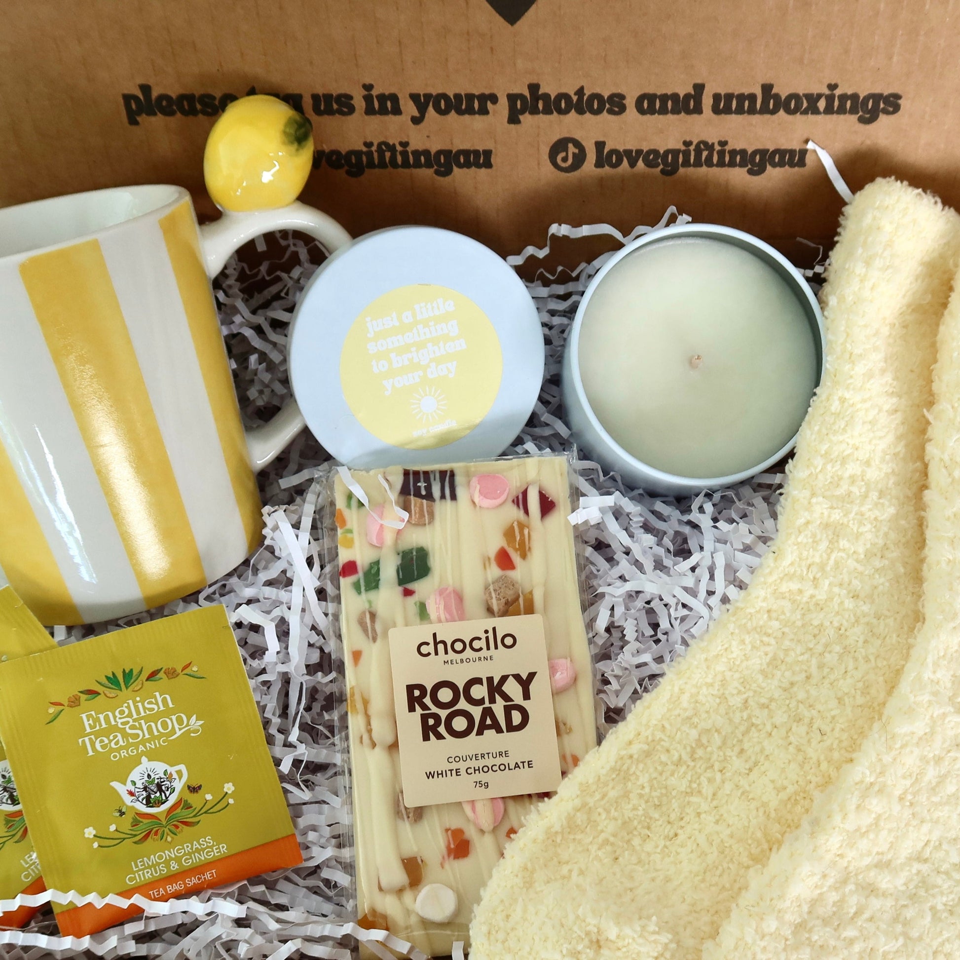 Gifting box with a mug, lemon, soap, candle, and Rocky Road chocolate bar.