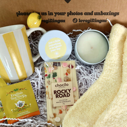 Gifting box with a mug, lemon, soap, candle, and Rocky Road chocolate bar.