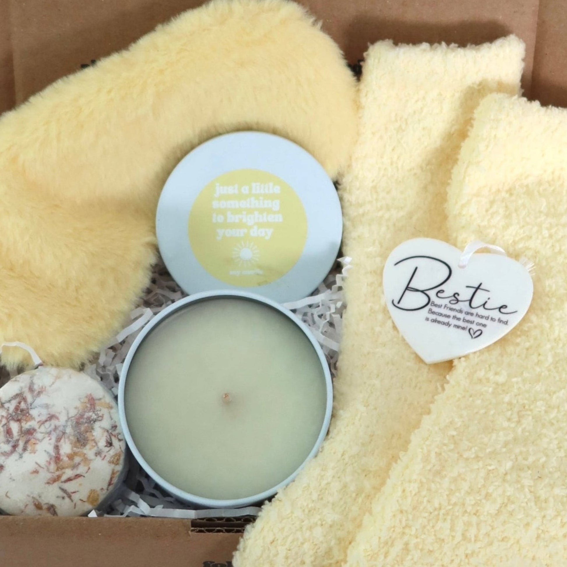 Gift box with yellow socks, candle, and other items on a white background