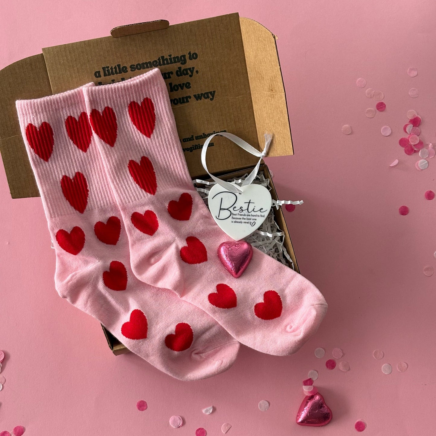 Pink socks with red hearts on a pink background with confetti