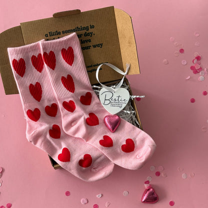 Pink socks with red hearts on a pink background with confetti