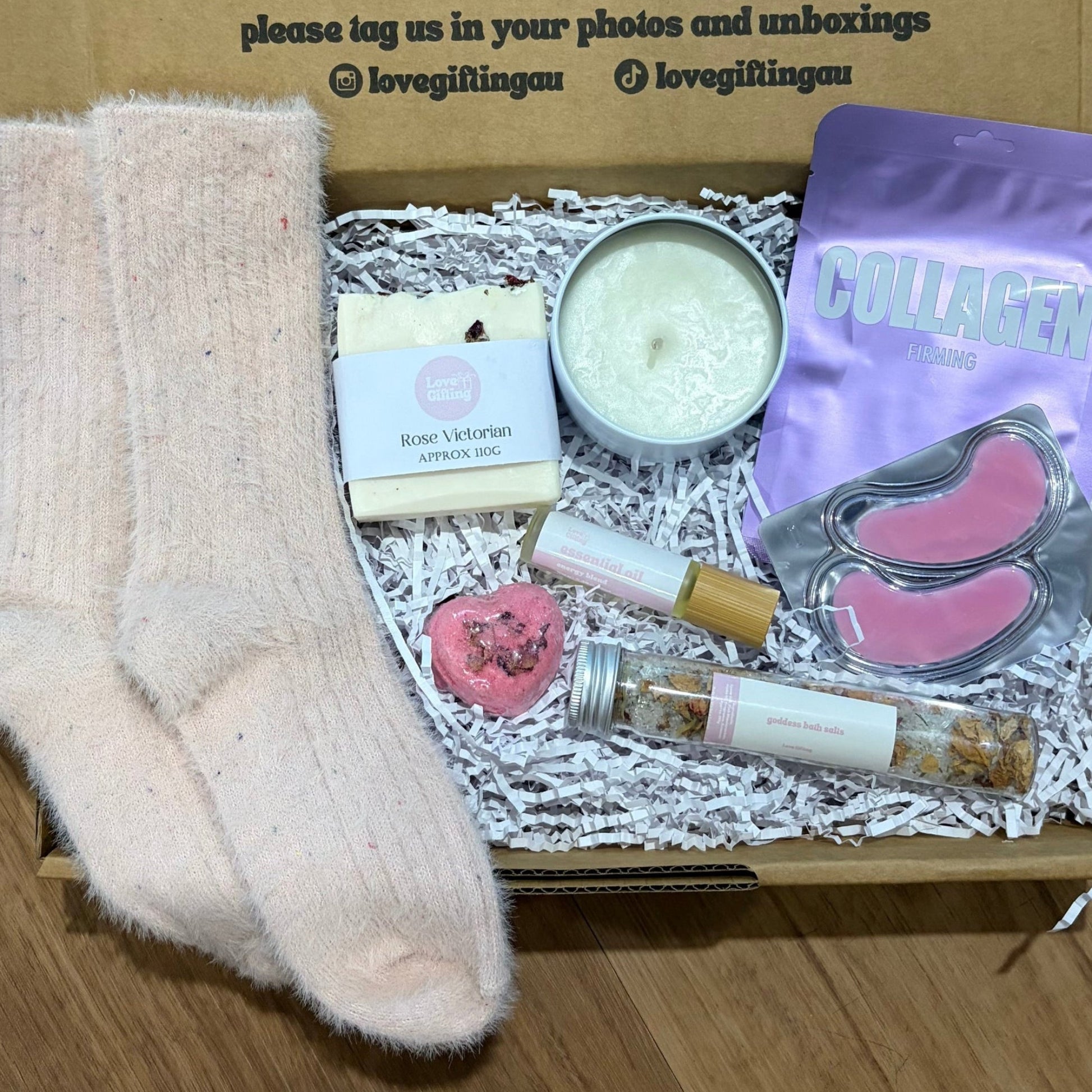 Pamper Self Care Gift box with socks, candle, and other items on a wooden surface