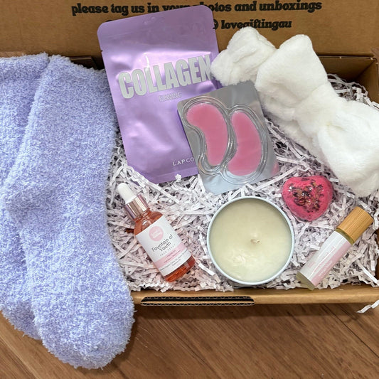 Gift box with socks, soap, and candle on a wooden surface