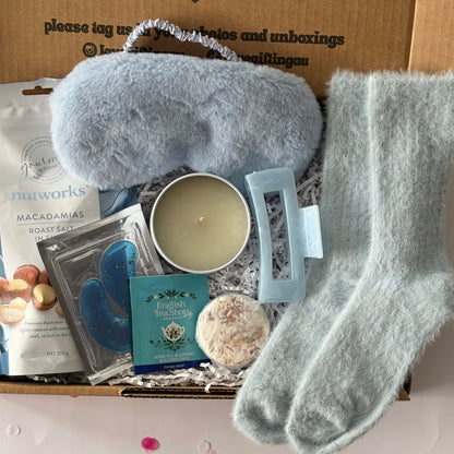 Relaxation kit with eye mask, socks, and candle on a box