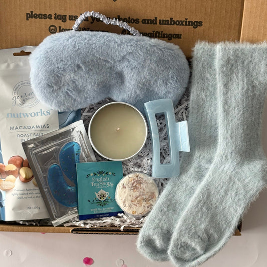 Relaxation kit with eye mask, socks, and candle on a box