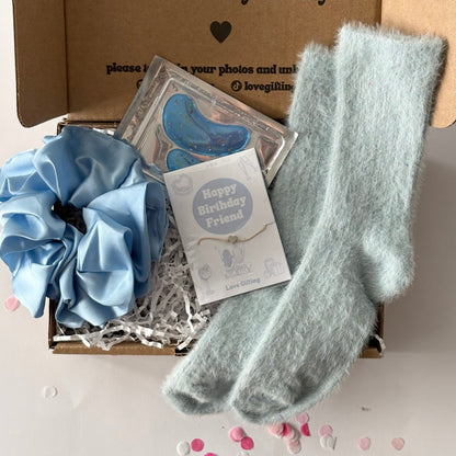 Gift box with blue scrunchie, socks, and card on a light background