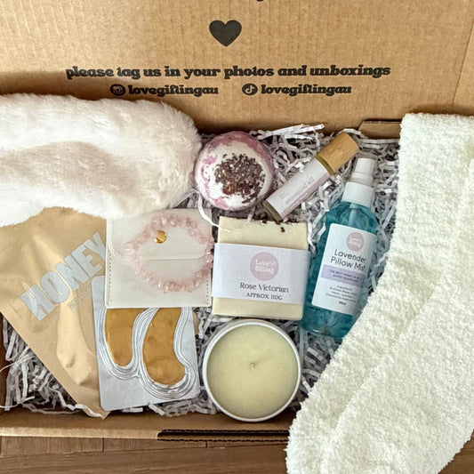 Box of self-care items with a message on the lid, including socks and a candle.