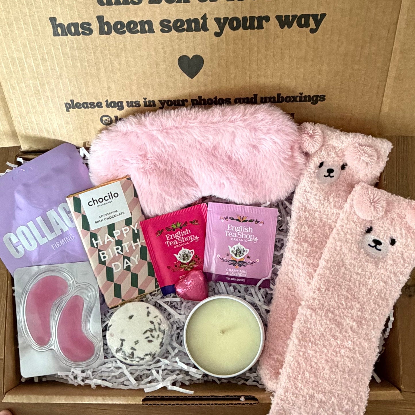 Box of self-care items including socks, a candle, and a card with a message.