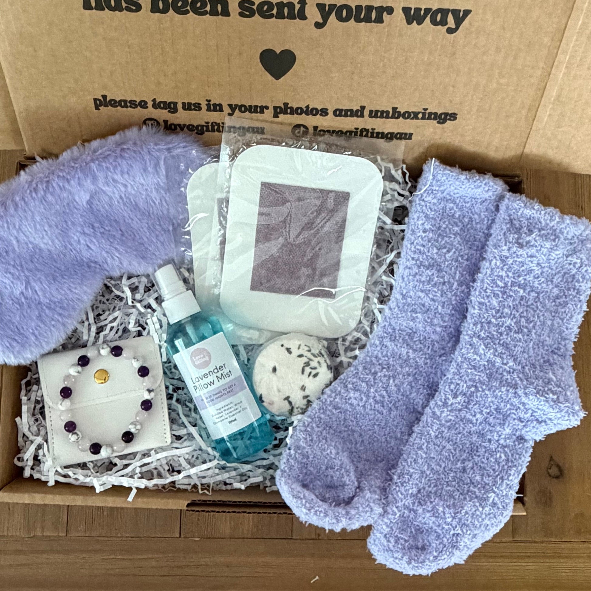 Box of  sleep self-care items with a message on the lid, including socks and a bottle.