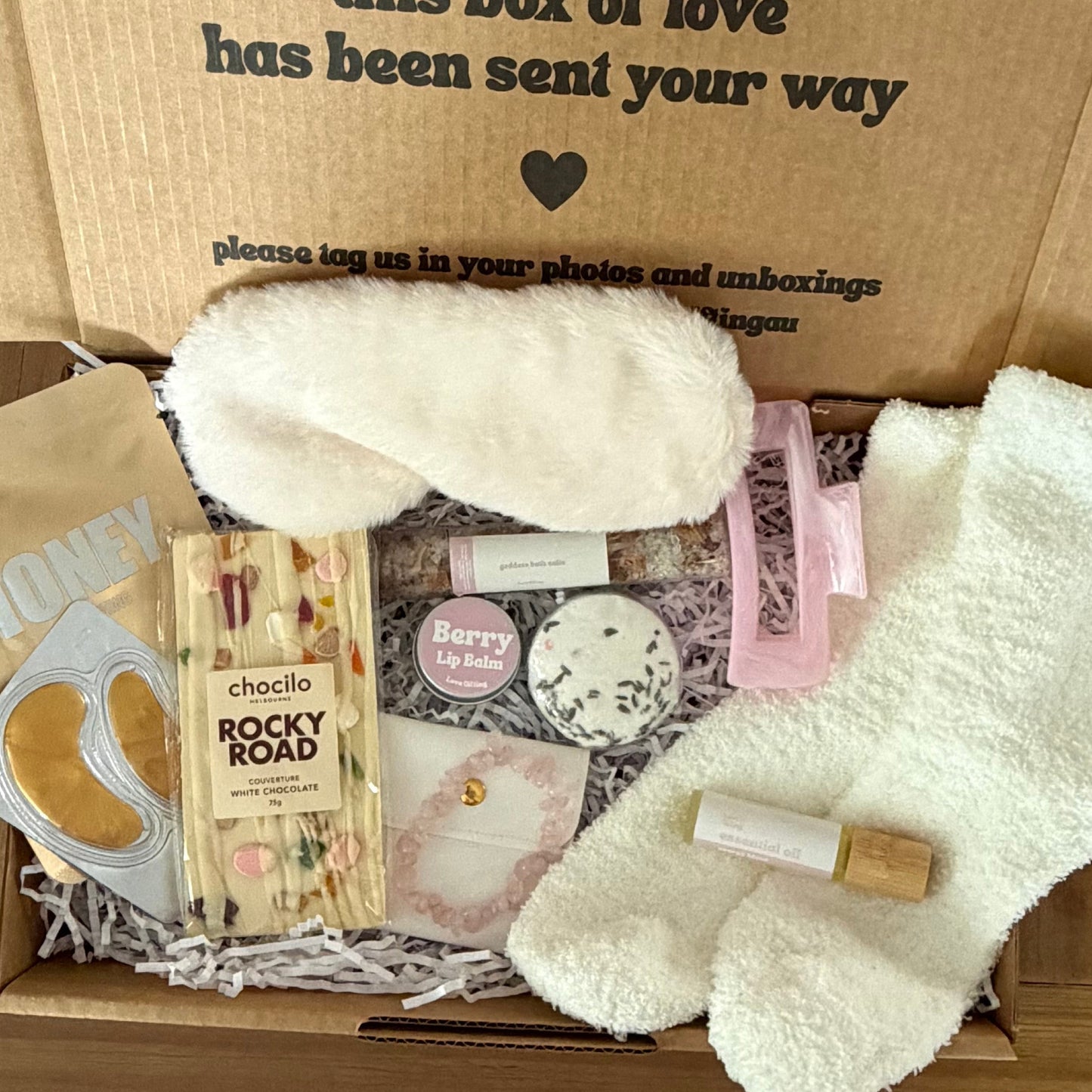 Box of care items with a message on the lid, placed on a wooden surface.