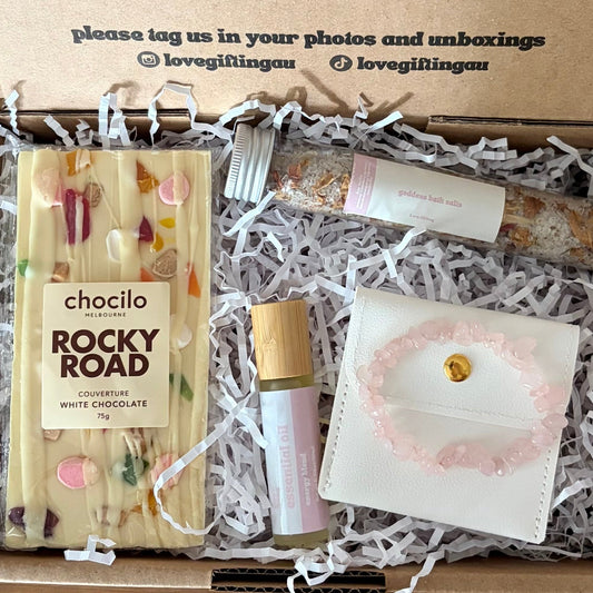 Unboxed gift set with Rocky Road chocolate bar, lip balm, and small pouch on crinkled paper.