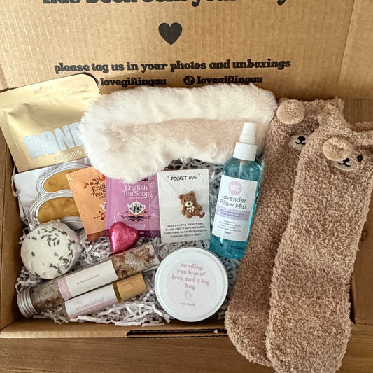 Box of self-care items with a message on a wooden floor.