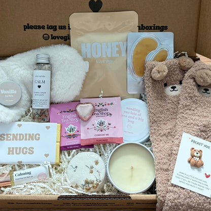 Box of care items with a teddy bear-themed gift on a wooden surface