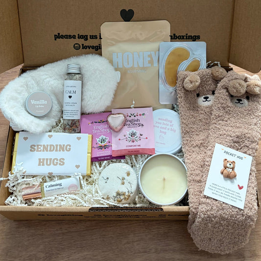 Box of care items with a teddy bear-themed gift on a wooden surface