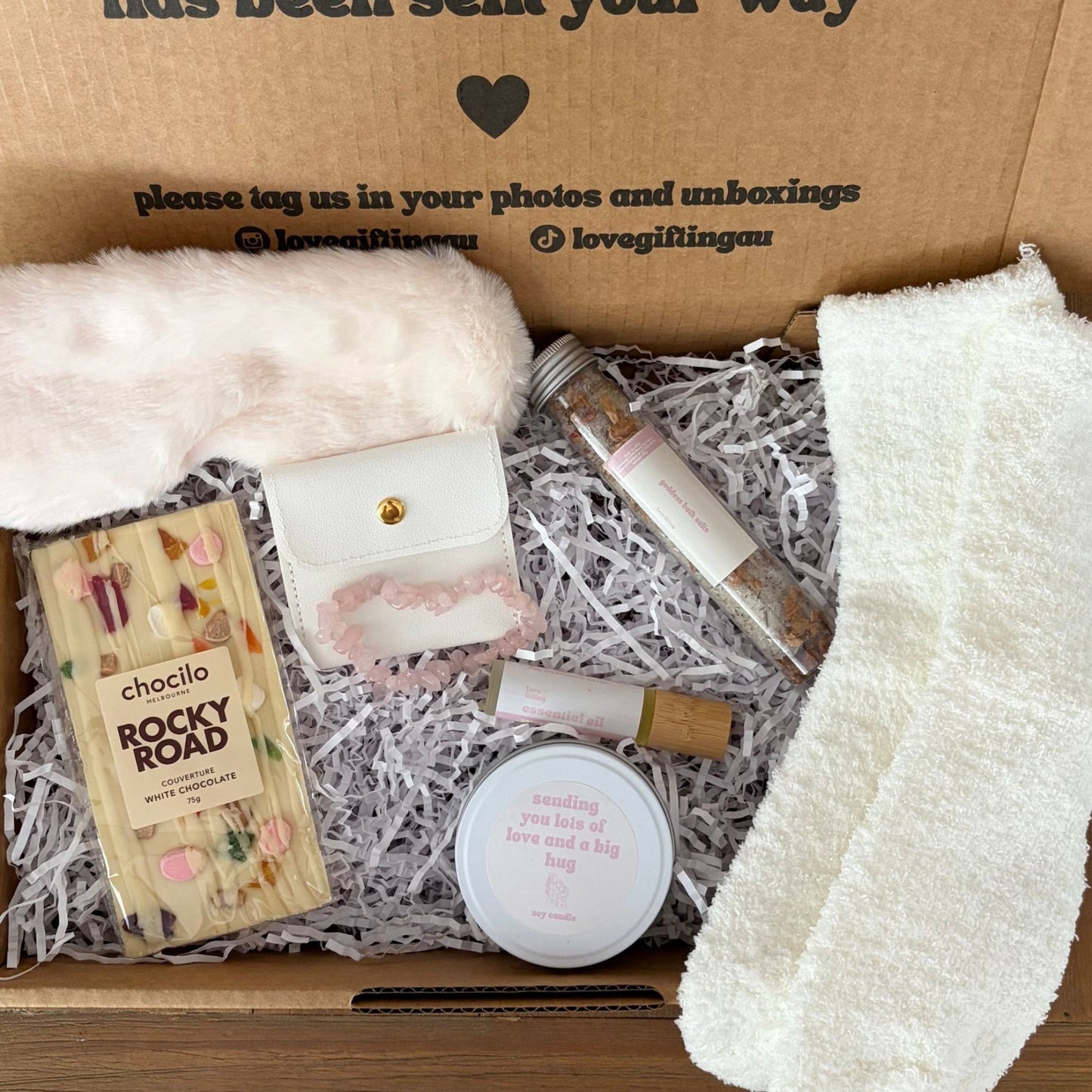 Box of self-care items including socks, soap, and a book with a message inside.