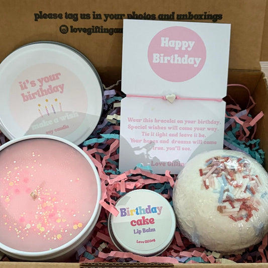 Birthday Gift box with candles, bath bomb, and card on a wooden surface