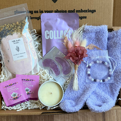 Box of self-care items including socks, soap, and a candle with a message on the box.