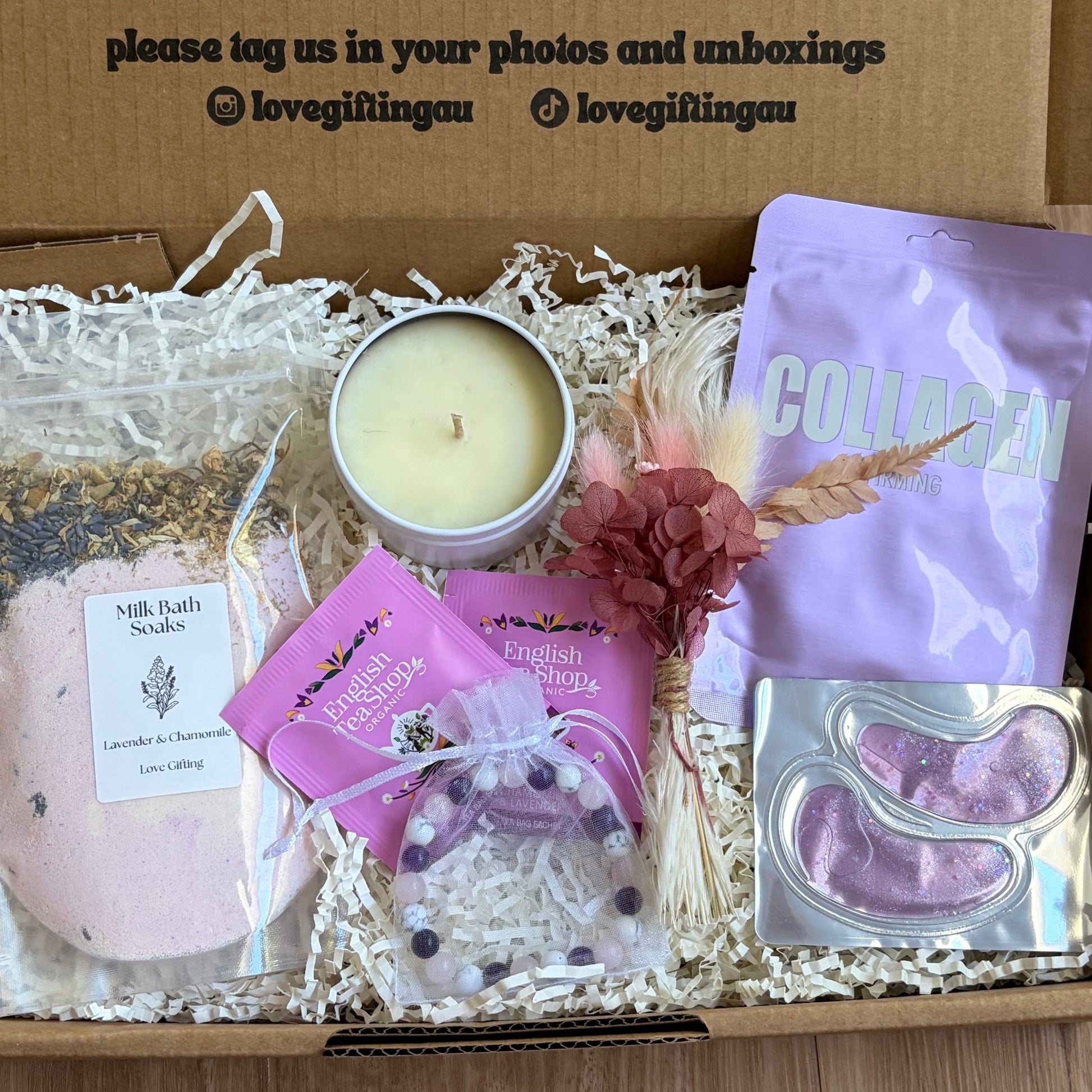 Gift box with candles, soap, and a card on a wooden surface
