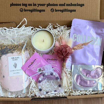 Gift box with candles, soap, and a card on a wooden surface