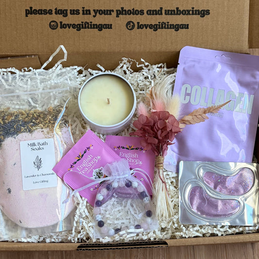 Gift box with candles, soap, and a card on a wooden surface