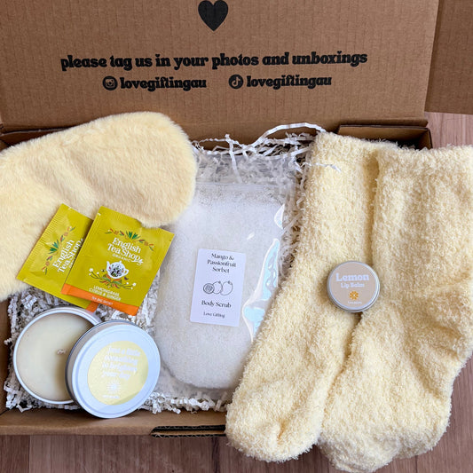 Gift box with bath bombs, soap, and fluffy socks on a wooden surface