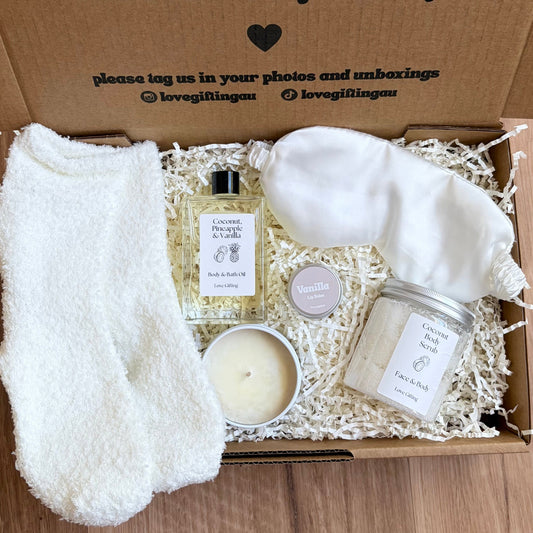 Gift box with a candle, soap, and other items on a wooden surface
