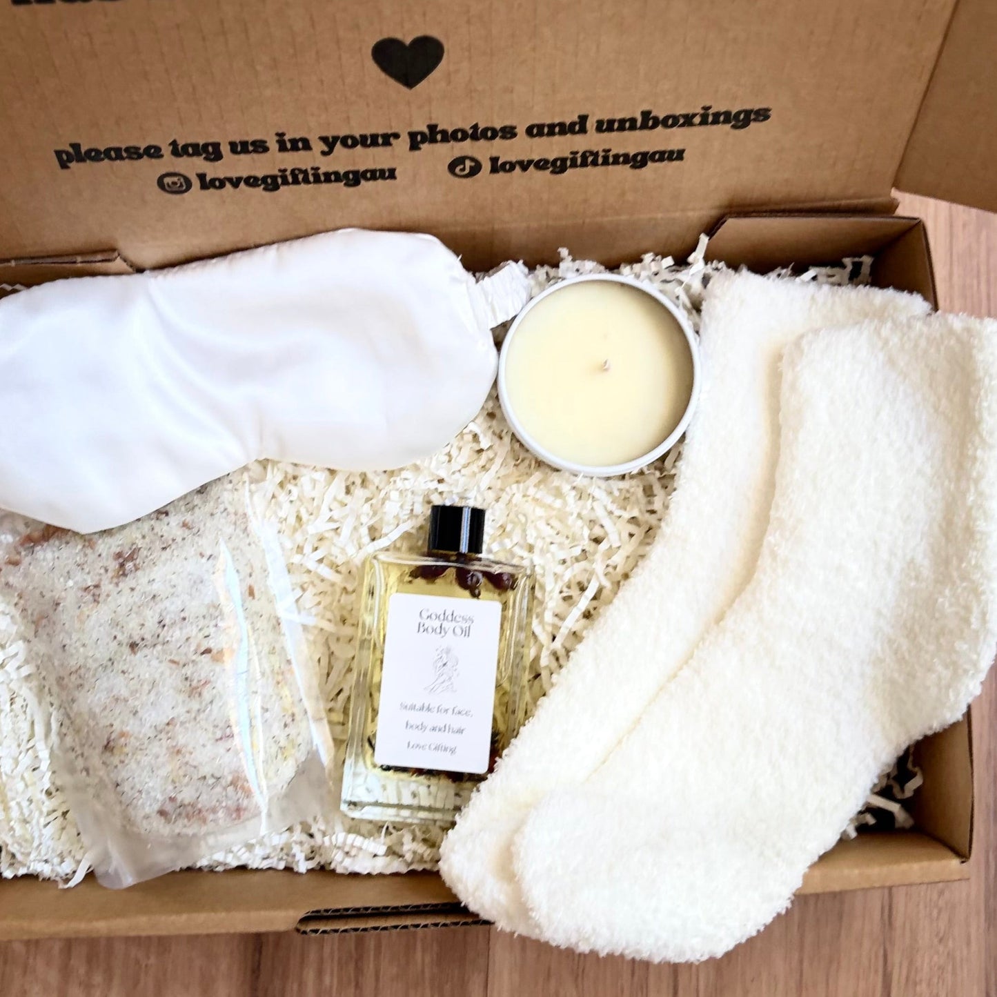 Gift box with a candle, soap, and other items on a wooden surface