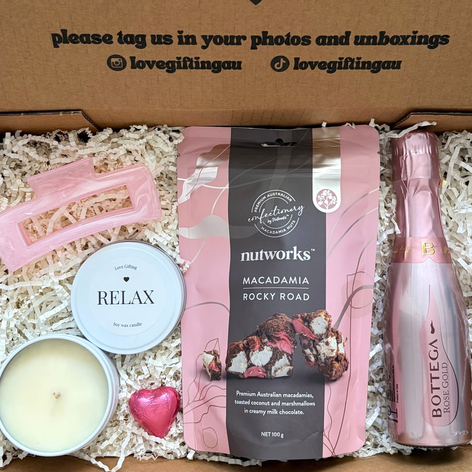 Gift box with a bottle, candle, and macadamia rocky road, featuring a message of encouragement.