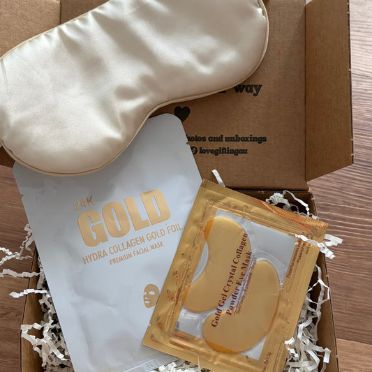 Box containing a gold sleep mask and face masks on a wooden surface