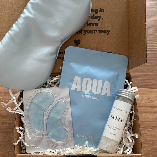 Box with sleep mask, eye masks, and other items on a wooden surface