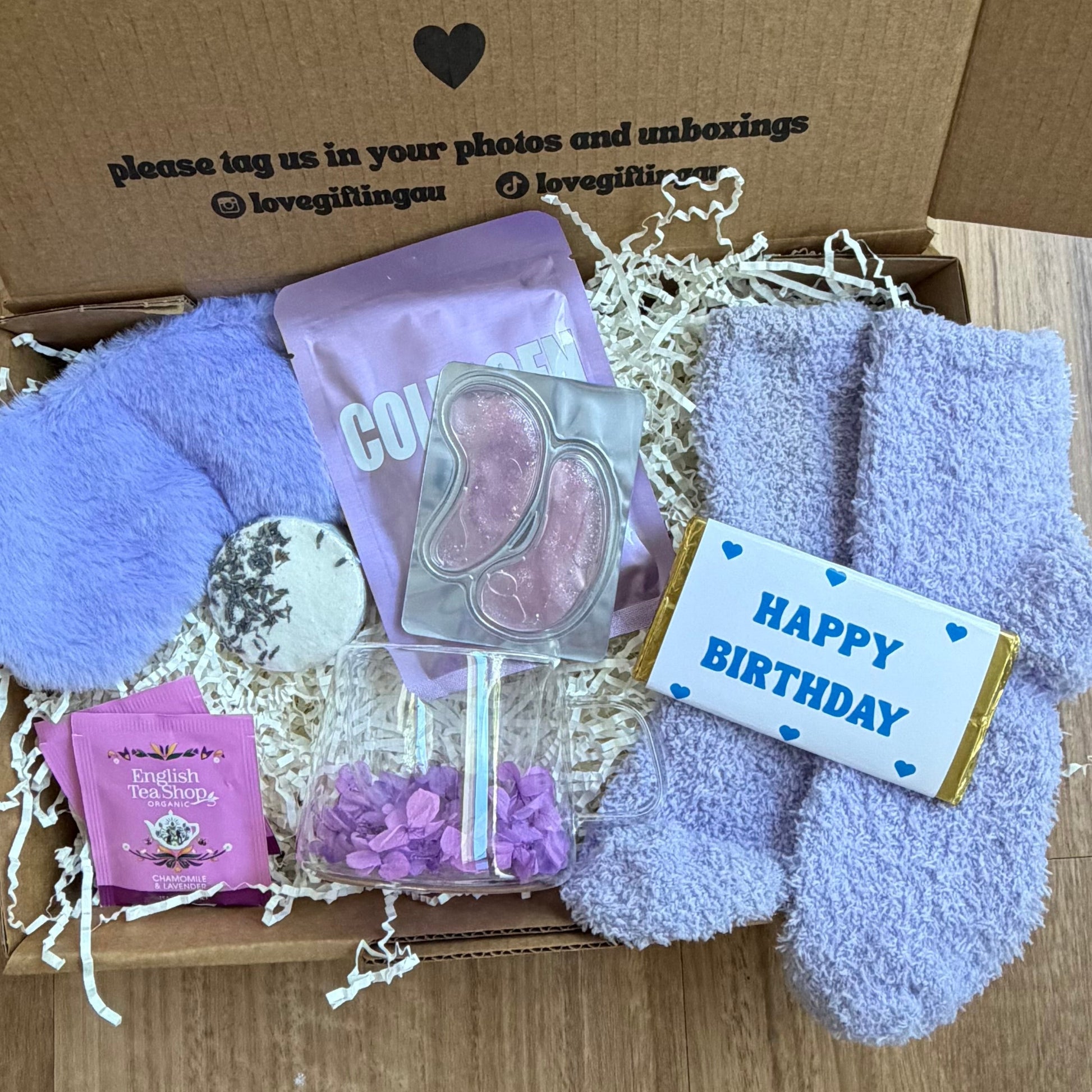 Gift box with plush toys, a card, and a small gift on a wooden floor.